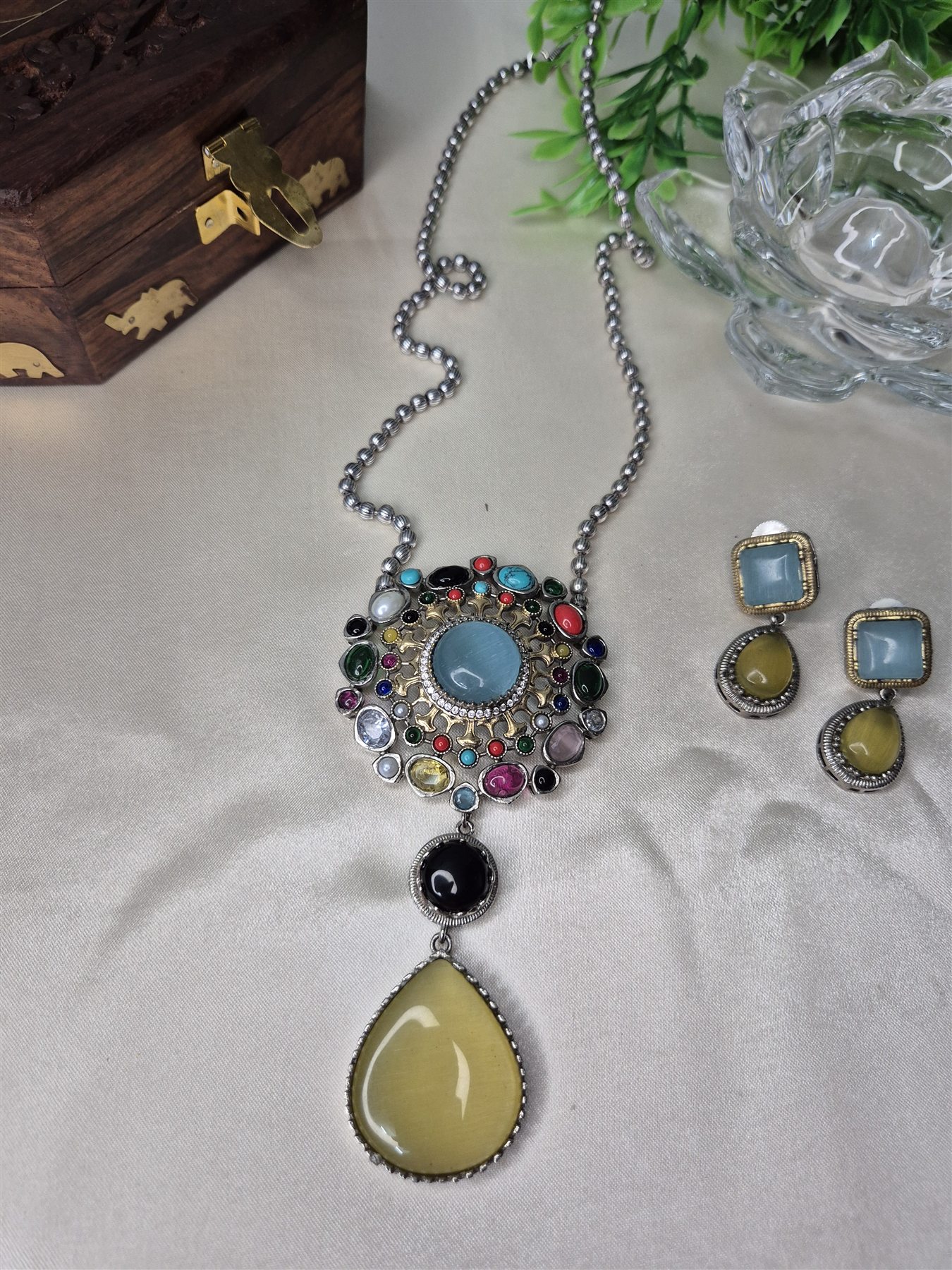 Colourful statement pendant and earrings arranged on a wooden display